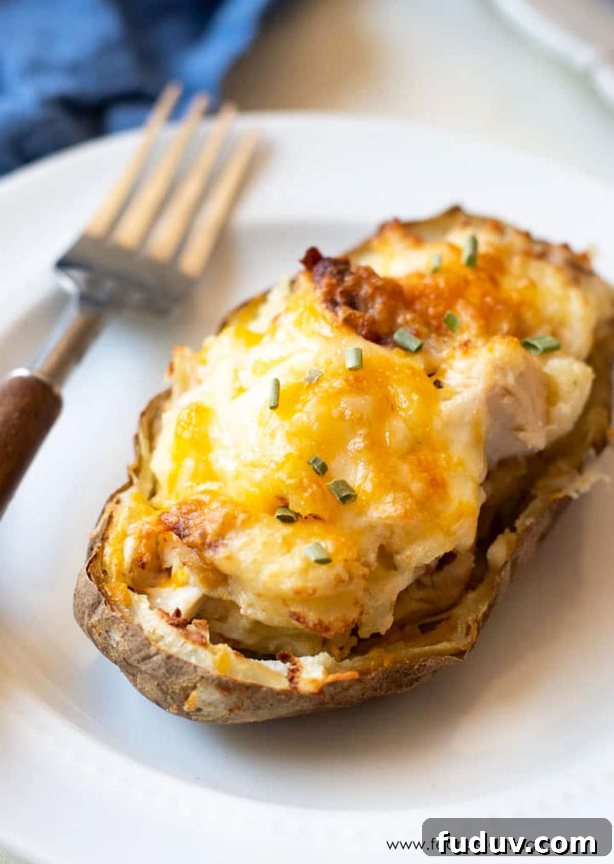 Air Fryer Twice-Baked Potatoes with Chicken and Crispy Bacon 2 A loaded air fryer twice baked potato on a small white plate.