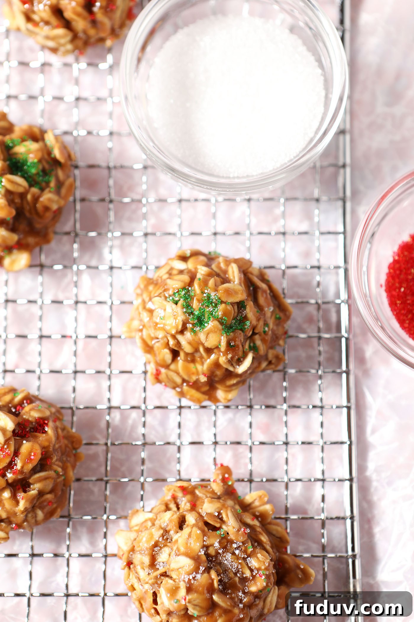 Close up of no bake cookie butter cookies on a wire rack next to colored sugars over a pink terrazzo surface