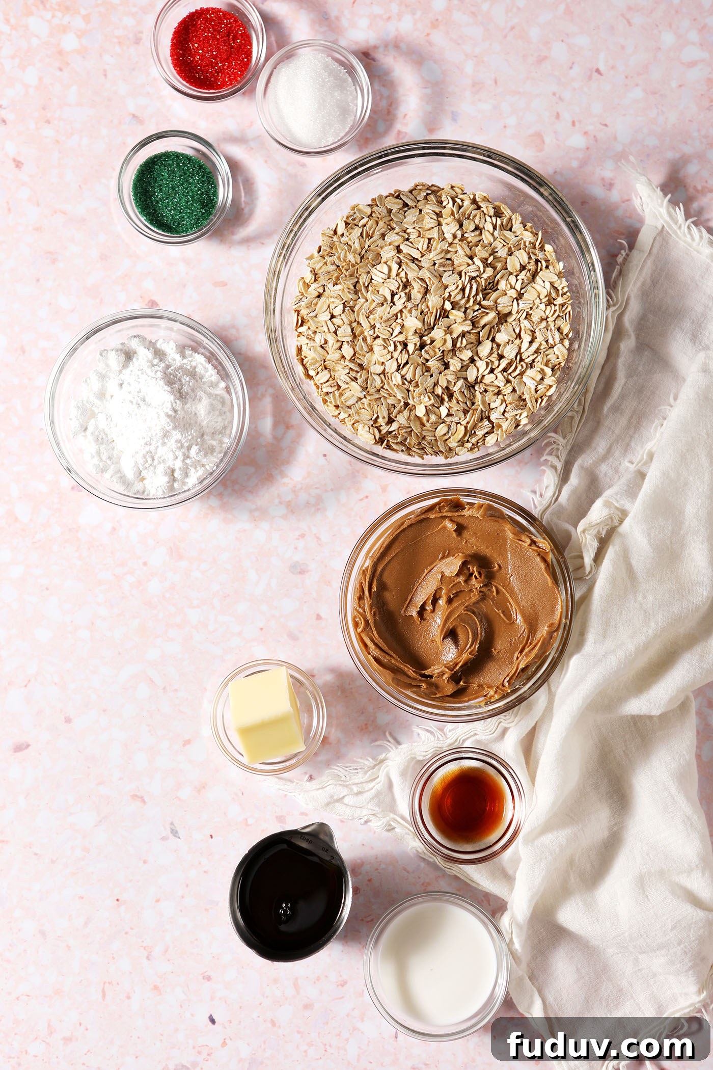 Ingredients to make no bake cookie butter cookies in bowls on a pink terrazzo surface next to a white linen