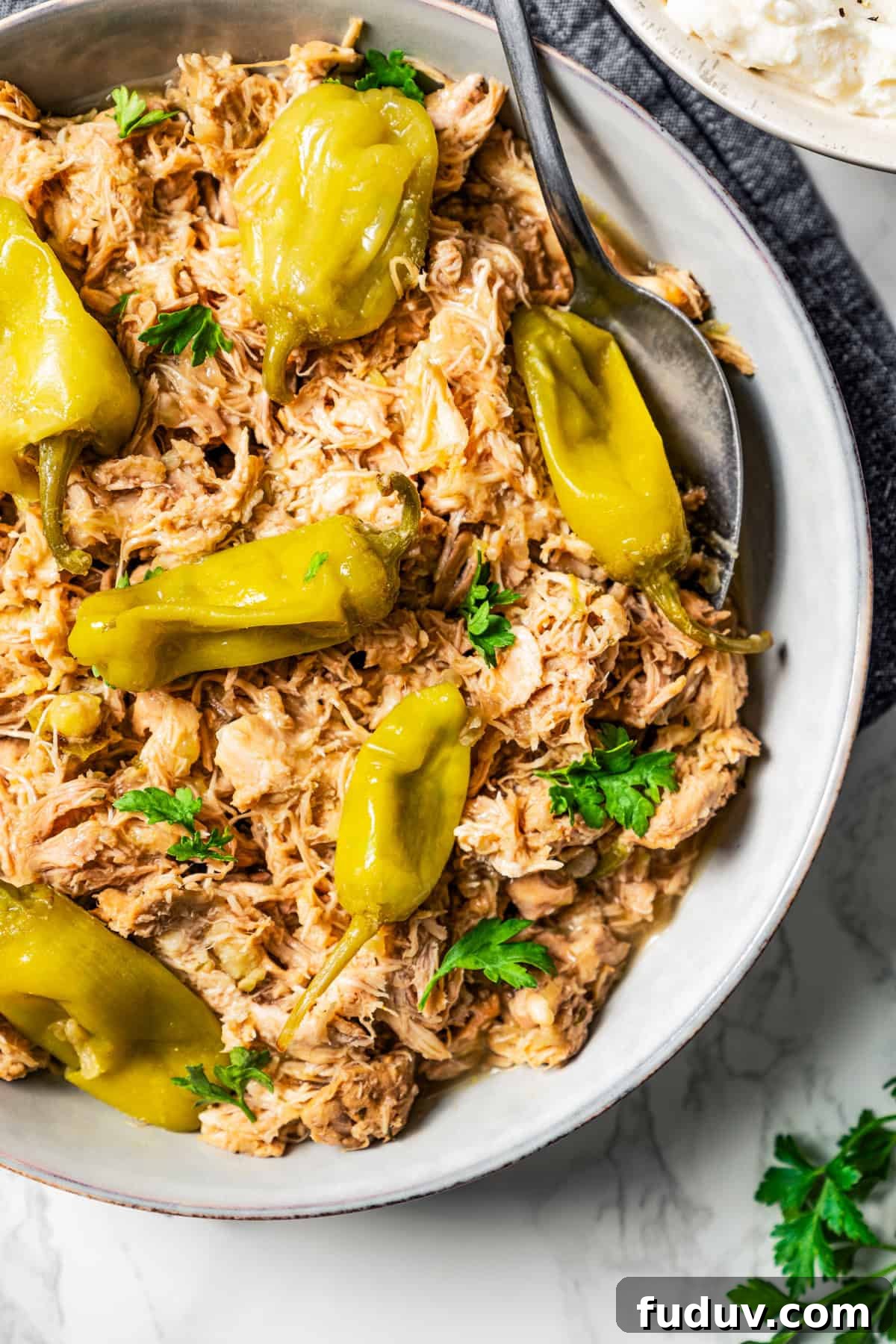 Mississippi chicken is an easy crock pot recipe with juicy chicken shredded in savory pepperoncini ranch sauce. Make it with 5 ingredients! Shredded Mississippi chicken and pepperoncini in a bowl.