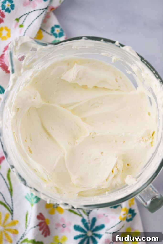A large glass bowl filled with whipped cream and cream cheese mixture on a table.