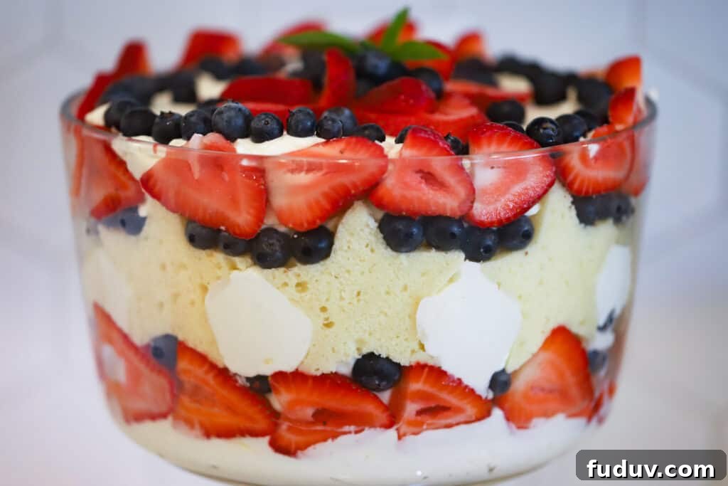 The side view of a 4th of july Berry Trifle made with strawberries, blueberries, pound cake and decorated with a sprig of mint.