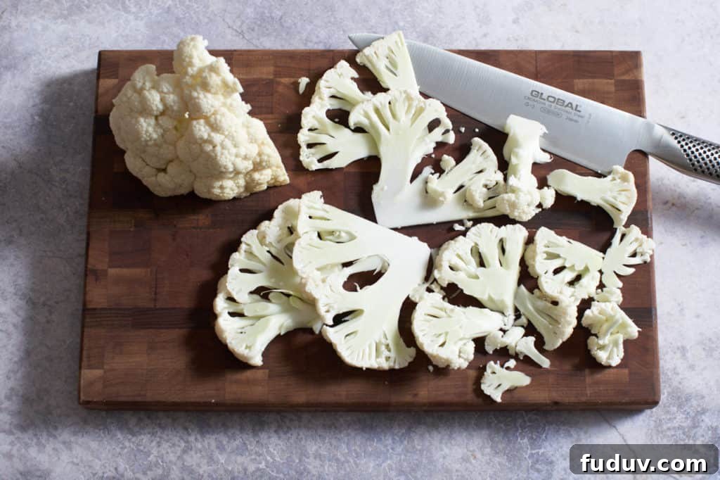 Sliced cauliflower and a chef's knife on a wooden cutting board.