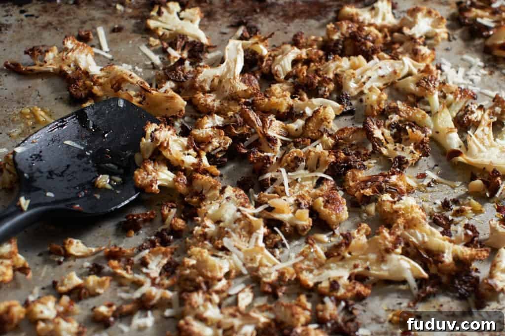 Crispy roasted cauliflower topped with parmesan cheese on a white plate.