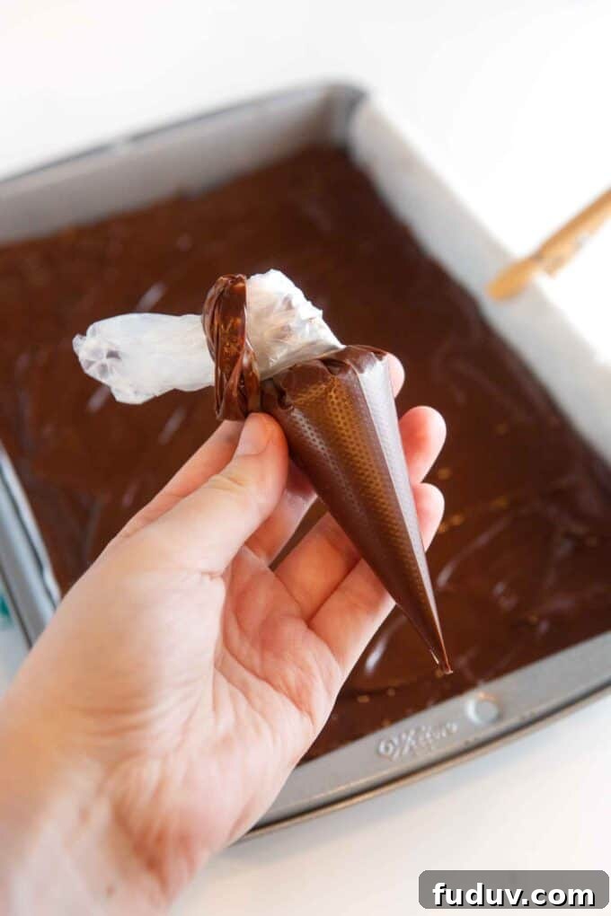Thin Mint Cookie Bars Recipe with Chocolate Ganache 11 hand holding small piping bag of chocolate