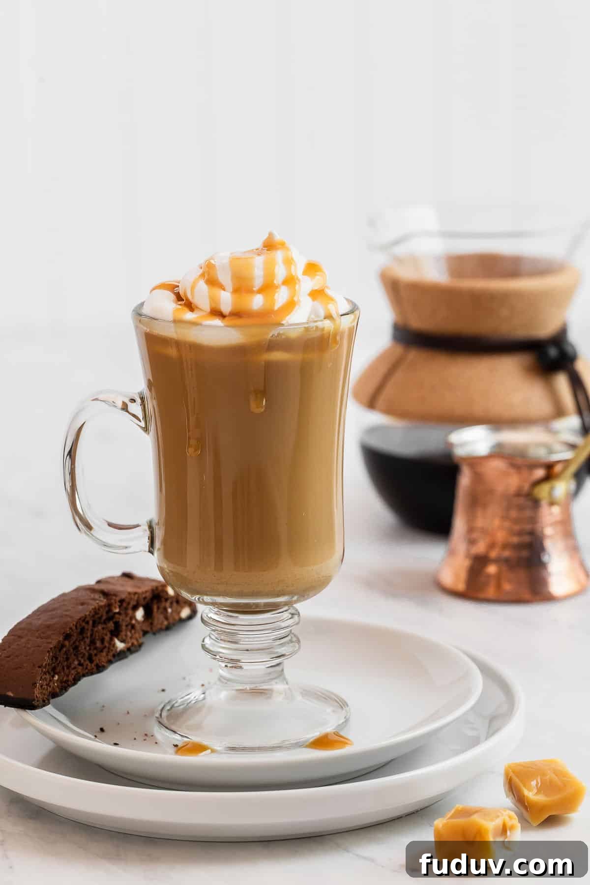 How to Make a Rich Caramel Latte at Home in Minutes 2 Caramel latte on plate with biscotti cookie on side.