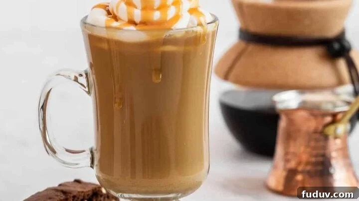 Caramel latte on plate with biscotti cookie on side.