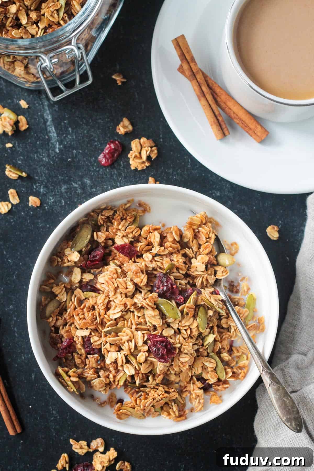 Vegan Pumpkin Spice Granola Recipe for Fall Breakfasts 2 Pumpkin spice granola with a splash of milk in a bowl next to a cup of coffee.