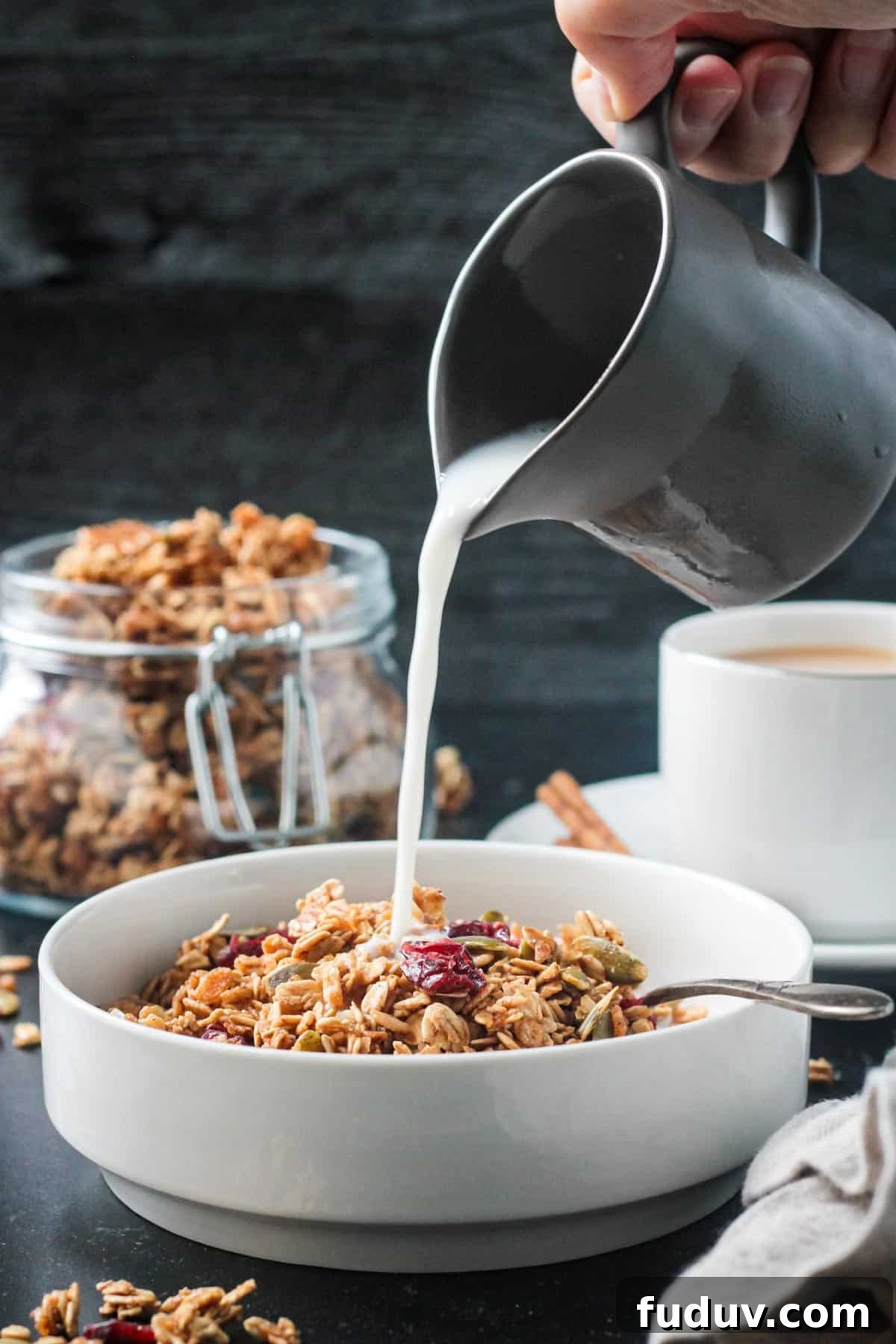 Vegan Pumpkin Spice Granola Recipe for Fall Breakfasts 11 Milk being poured from a small pitcher into a bowl of granola.