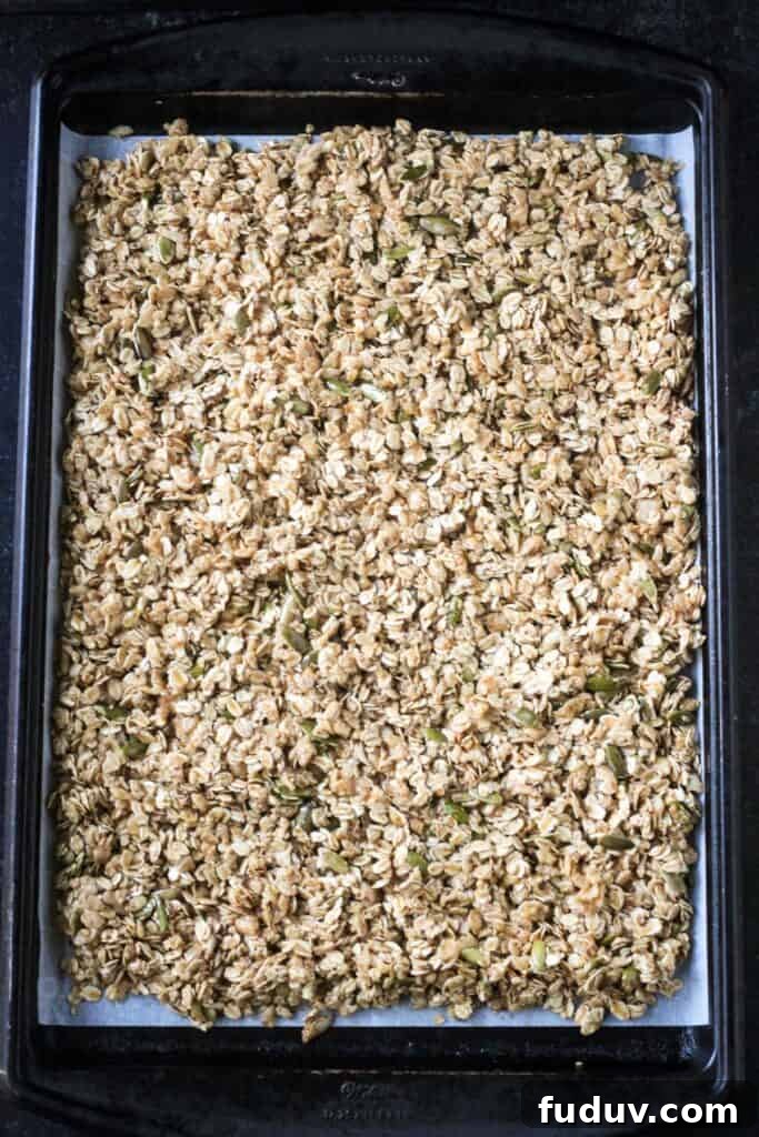 Vegan Pumpkin Spice Granola Recipe for Fall Breakfasts 7 Raw oat mixture spread out on a rimmed baking sheet.