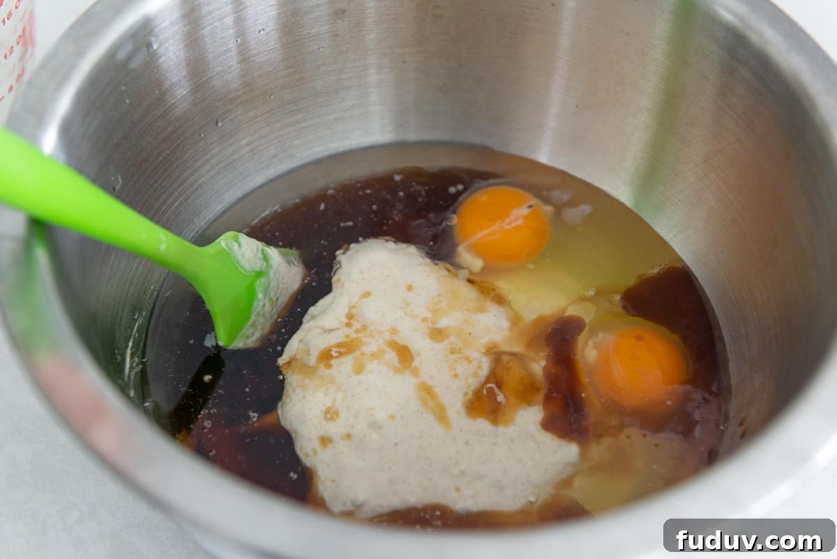 Sourdough discard in bowl with eggs, oil, maple syrup, and vanilla