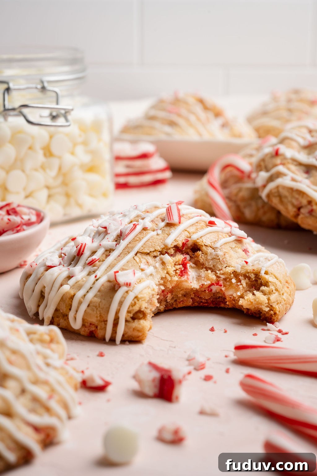 White Chocolate Peppermint Cookies Recipe for the Holidays 12 Close-up of a white chocolate peppermint cookie with a large bite taken out, showing the soft, chewy interior studded with white chocolate chips and peppermint pieces.
