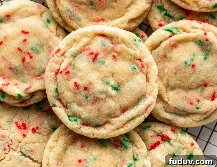 Close-up of Christmas sugar cookies with red and green sprinkles stacked on a wire rack, showing their soft, chewy texture and lightly sugared tops.