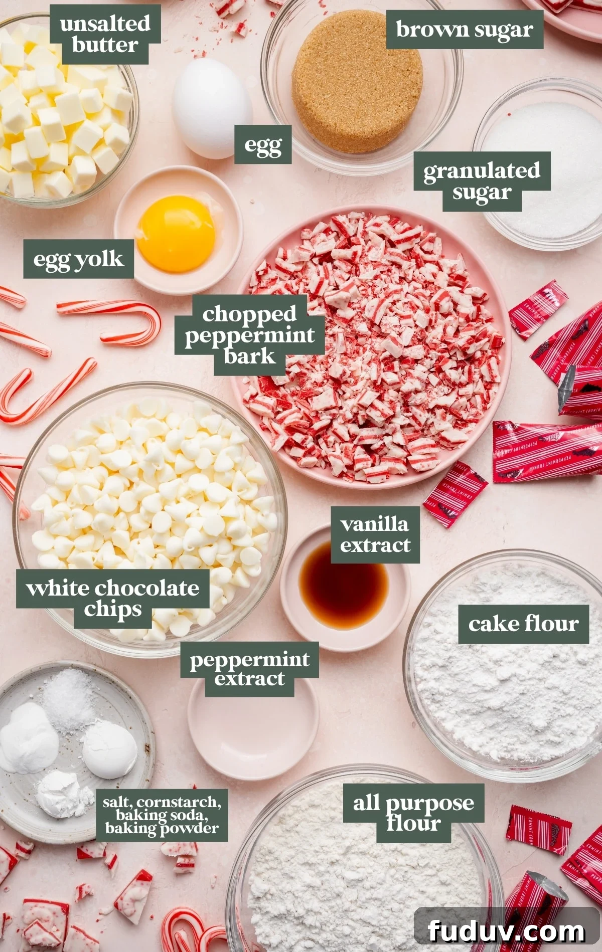 White Chocolate Peppermint Cookies Recipe for the Holidays 5 Overhead view of prepped ingredients for white chocolate peppermint cookies, including cubed butter, brown and granulated sugar, an egg and egg yolk, chopped peppermint bark, white chocolate chips, vanilla and peppermint extracts, cake flour, all-purpose flour, and small bowls of salt, cornstarch, baking soda, and baking powder.