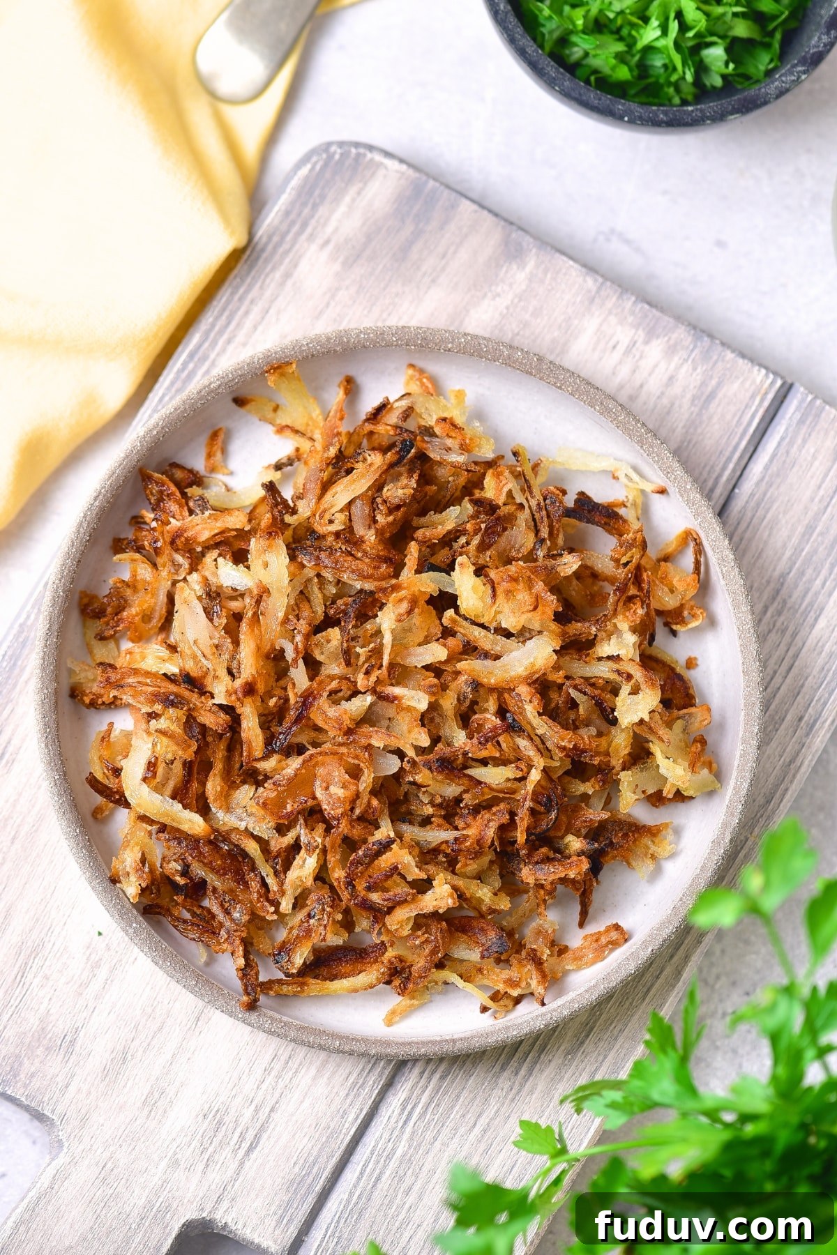 Top down view of a plate of gluten-free crispy fried onions on wooden board.
