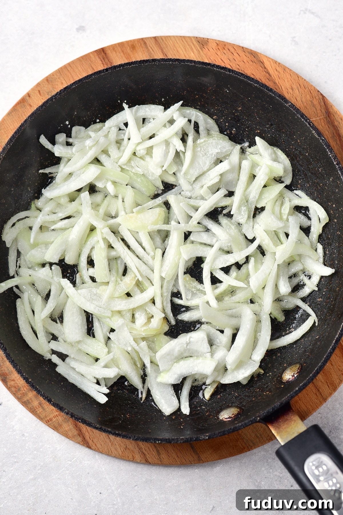 Frying onion slices in skillet.