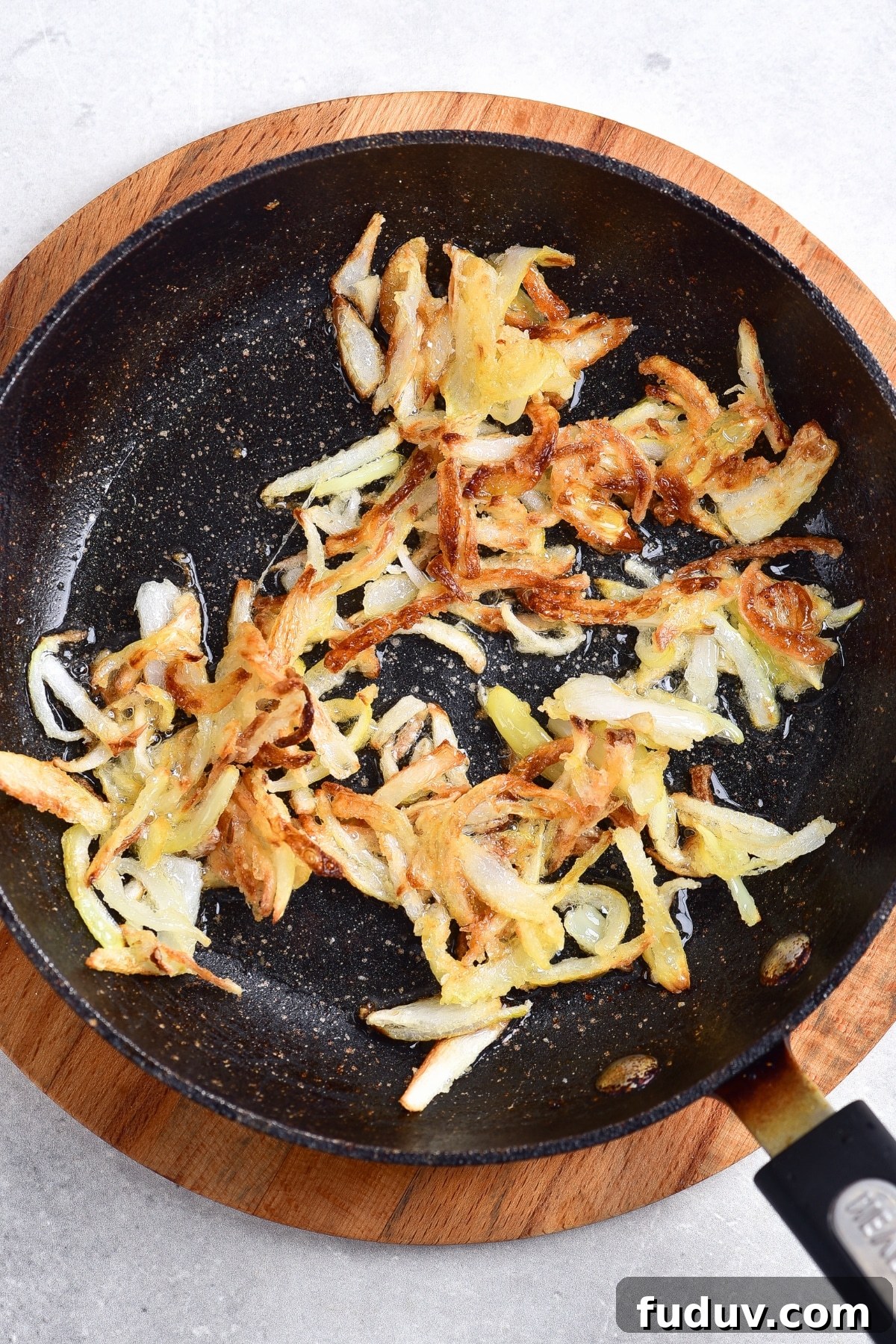 Golden brown fried onions in skillet.