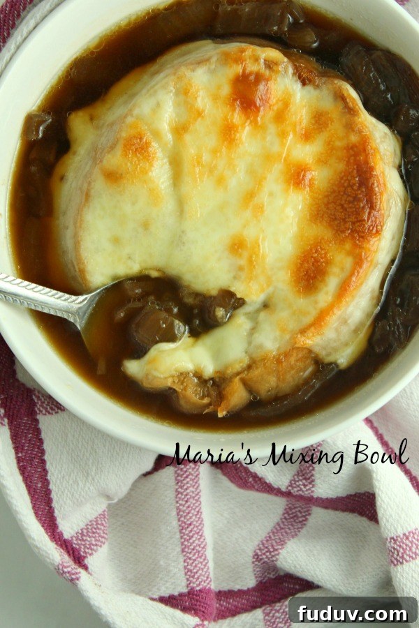 Slow Cooker French Onion Soup Spoon digging into slow cooker French onion soup in white bowl.