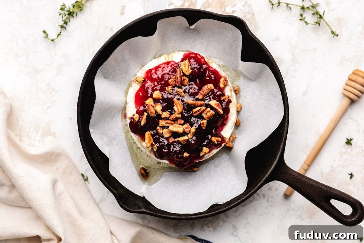 Pecans sprinkled over brie and cranberry sauce.