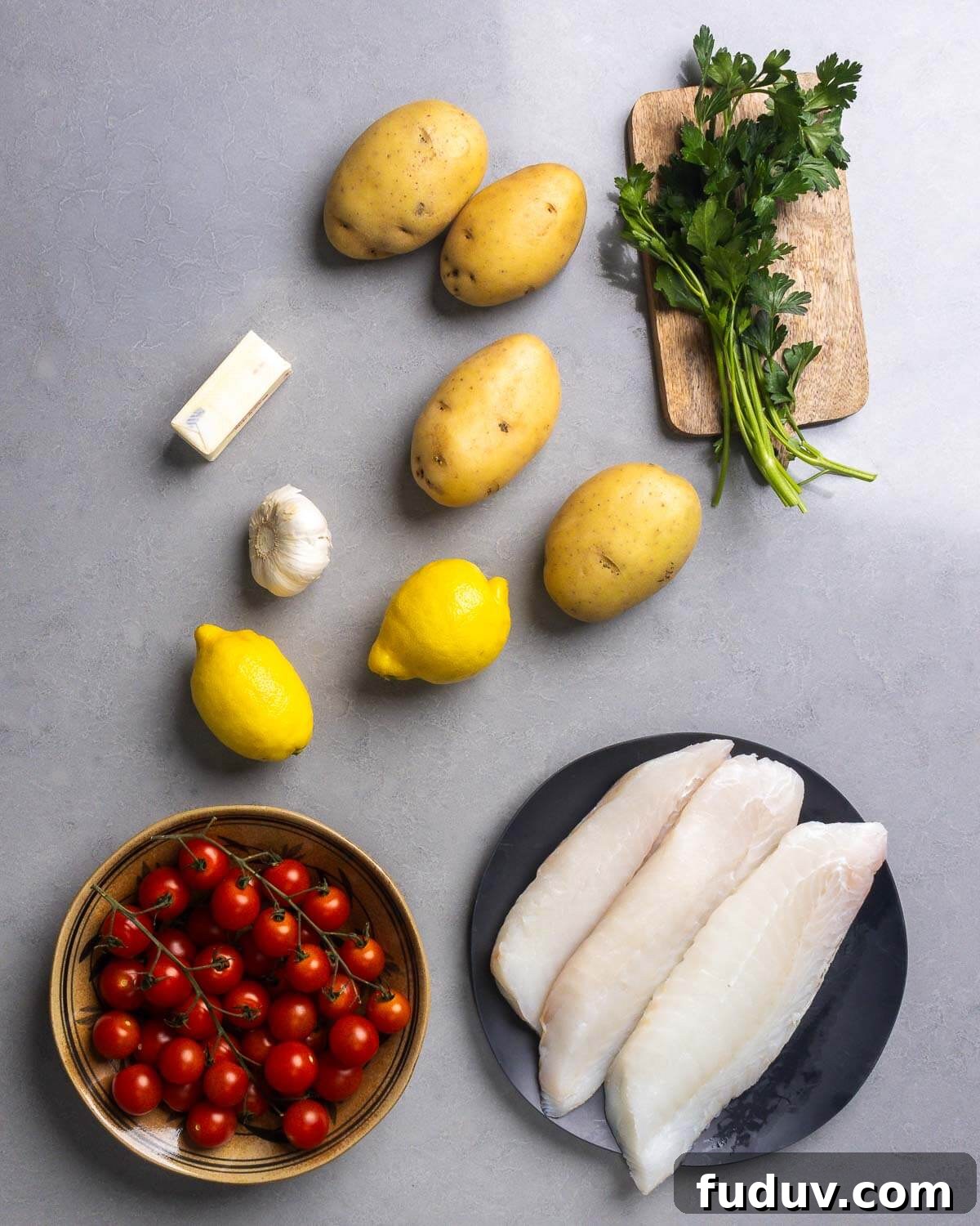 Ingredients shown: butter, potatoes, parsley, lemons, cherry tomatoes, and cod fillets.