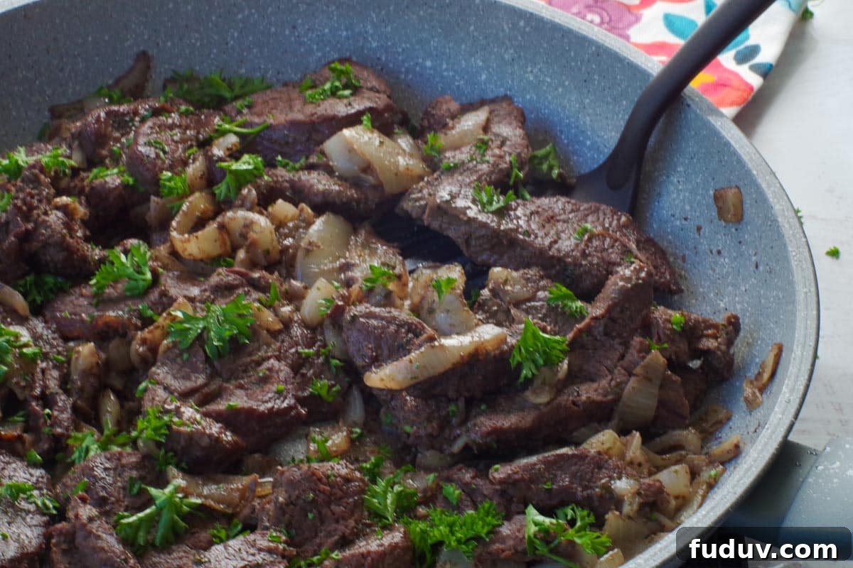 cooked venison steak in a skillet with a spatula turner