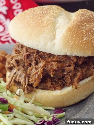 beef on a bun on a grey plate with coleslaw and beans