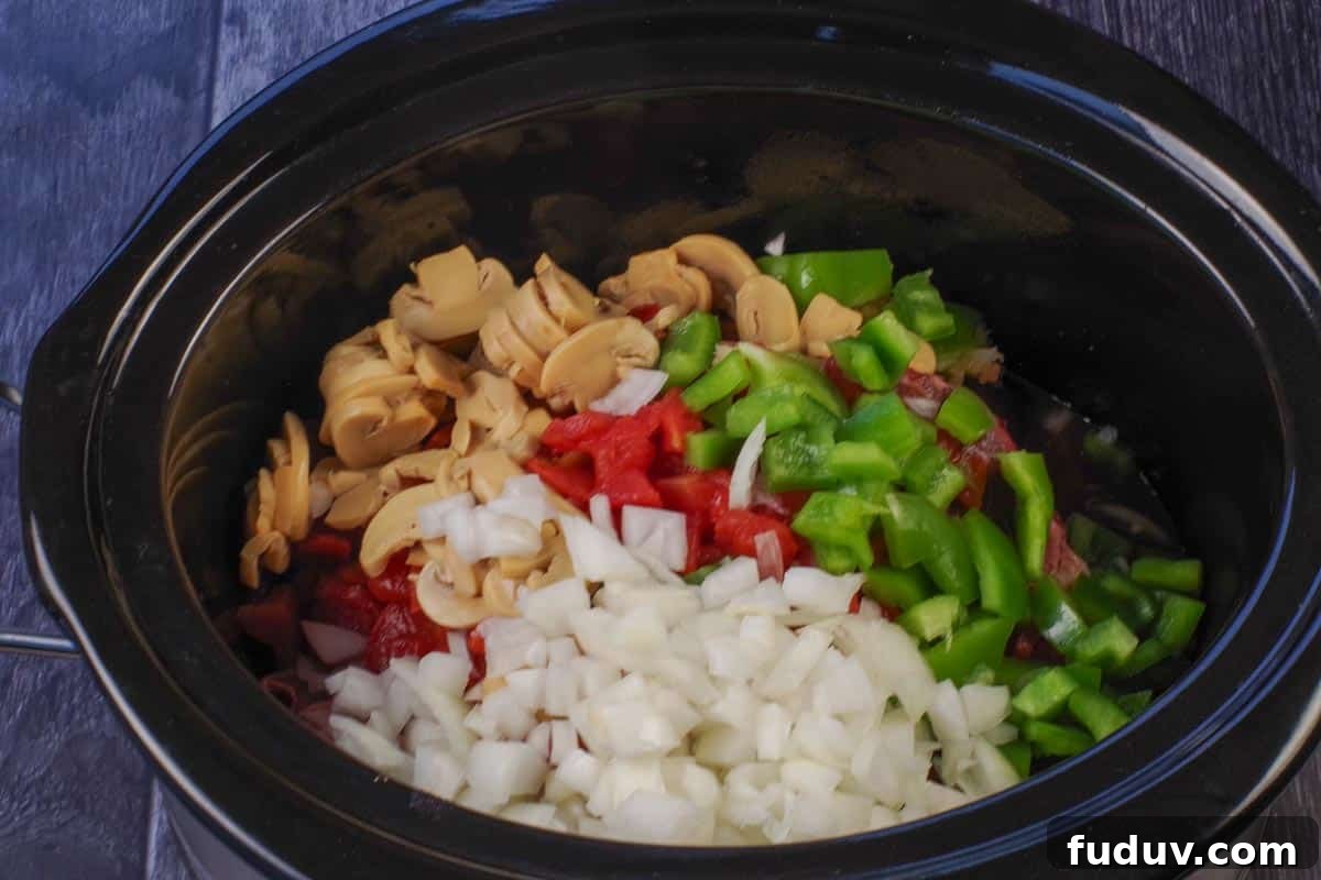 onion, diced tomatoes, green pepper and garlic added over steak in slow cooker