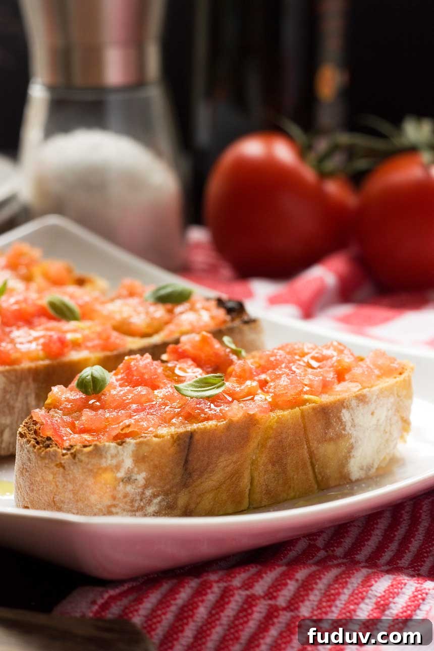 Pan con Tomate: Classic Spanish Tomato Toast Recipe 2 Spanish bruschetta (pan con tomate) close up on a white plate with ingredients behind