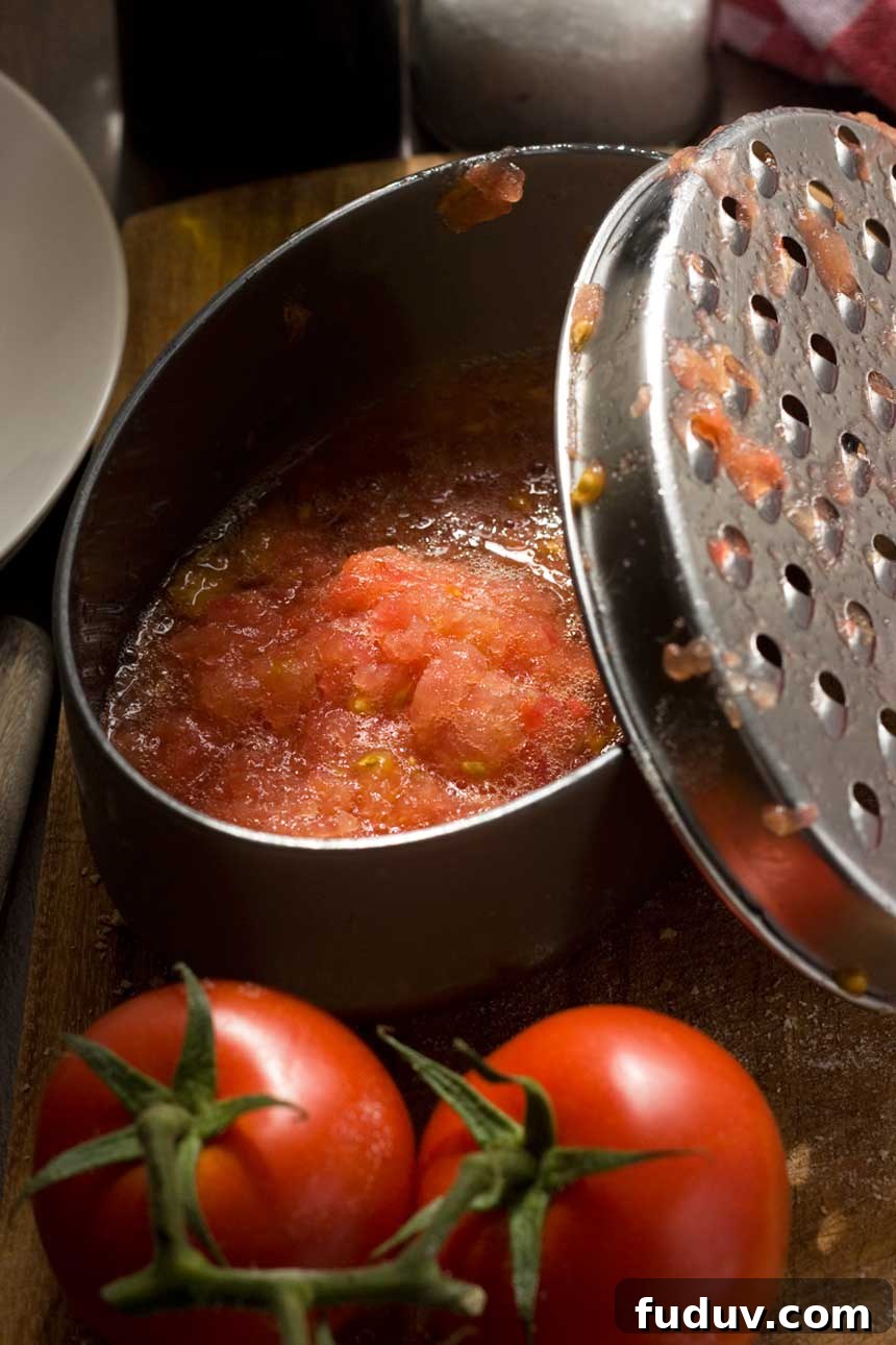 Pan con Tomate: Classic Spanish Tomato Toast Recipe 5 Grated tomato for pan con tomate in a container with tomatoes in the foreground.