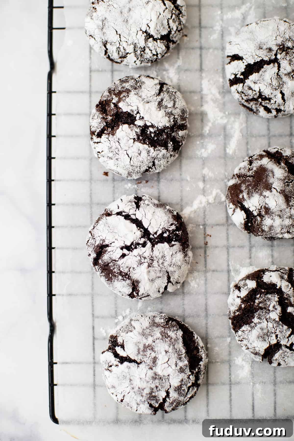 baked chocolate crinkle cookies on a black metal cooling rack.