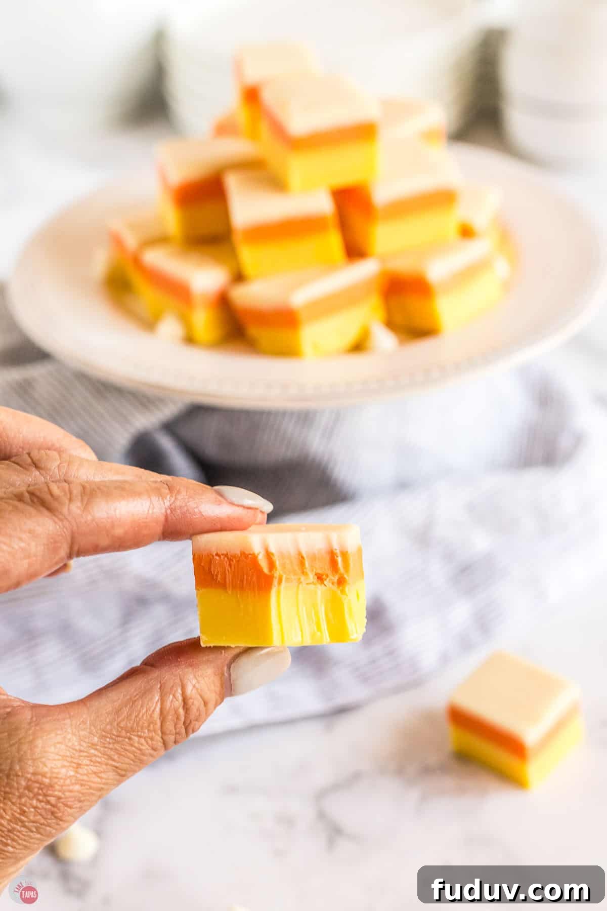 Candy Corn Fudge Recipe: Creamy Halloween Candy Treat 11 hand holding candy corn fudge with a bite in it