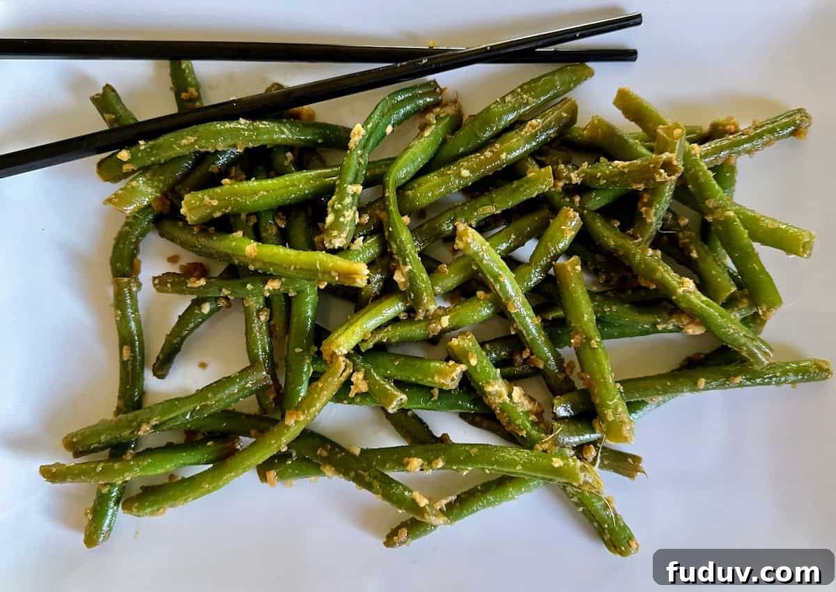 Asian style green beans recipe on a plate with chopsticks.