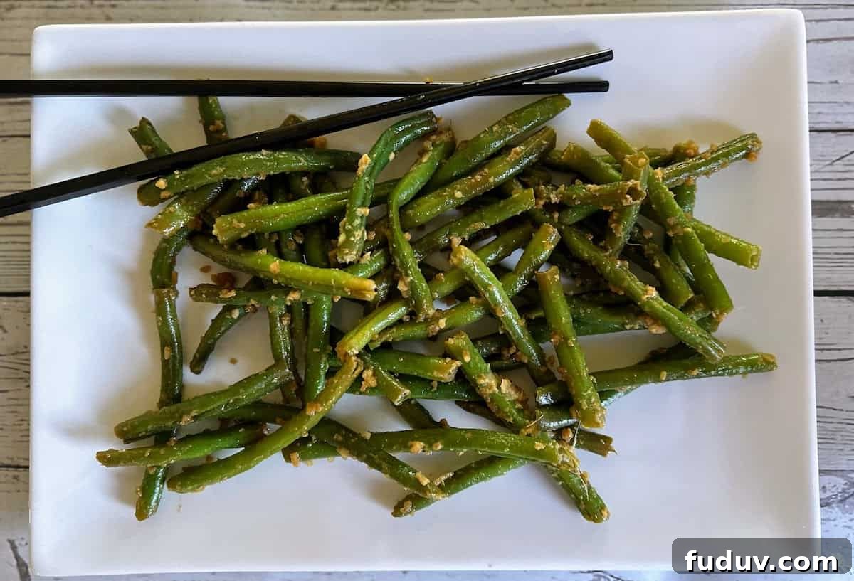 Asian-style green beans served on a platter with chopsticks.