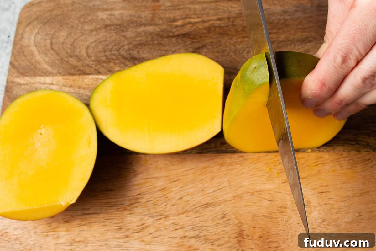A mango with but cheeks removed and the side being cut off.