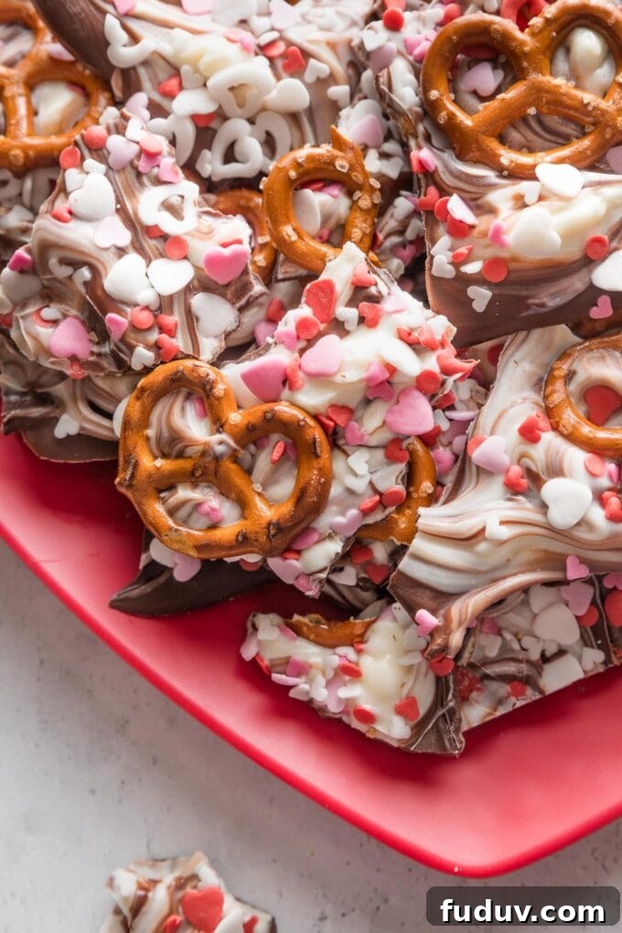 Close-up image of Valentine's bark with dark chocolate, white chocolate, pretzels, and sprinkles.