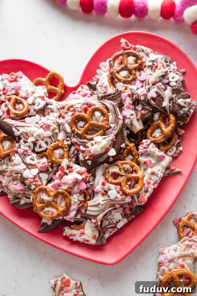 Chocolate pretzel bark with red and white heart sprinkled on a heart-shaped plate.