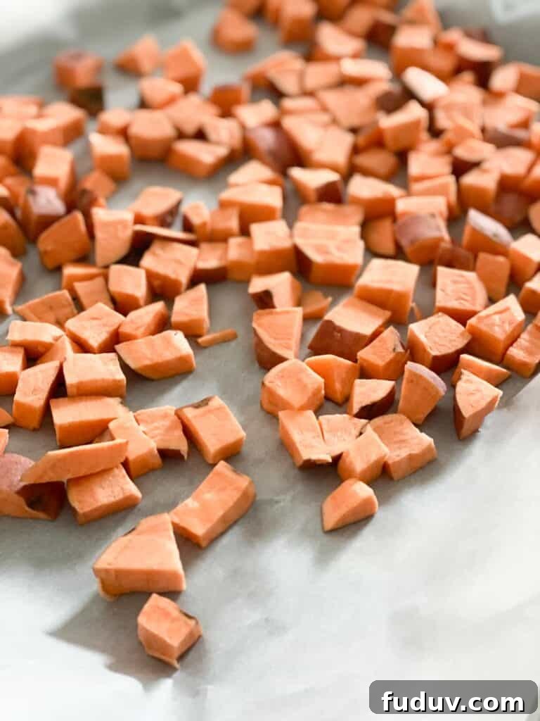 Raw, cut sweet potatoes on a baking sheet.