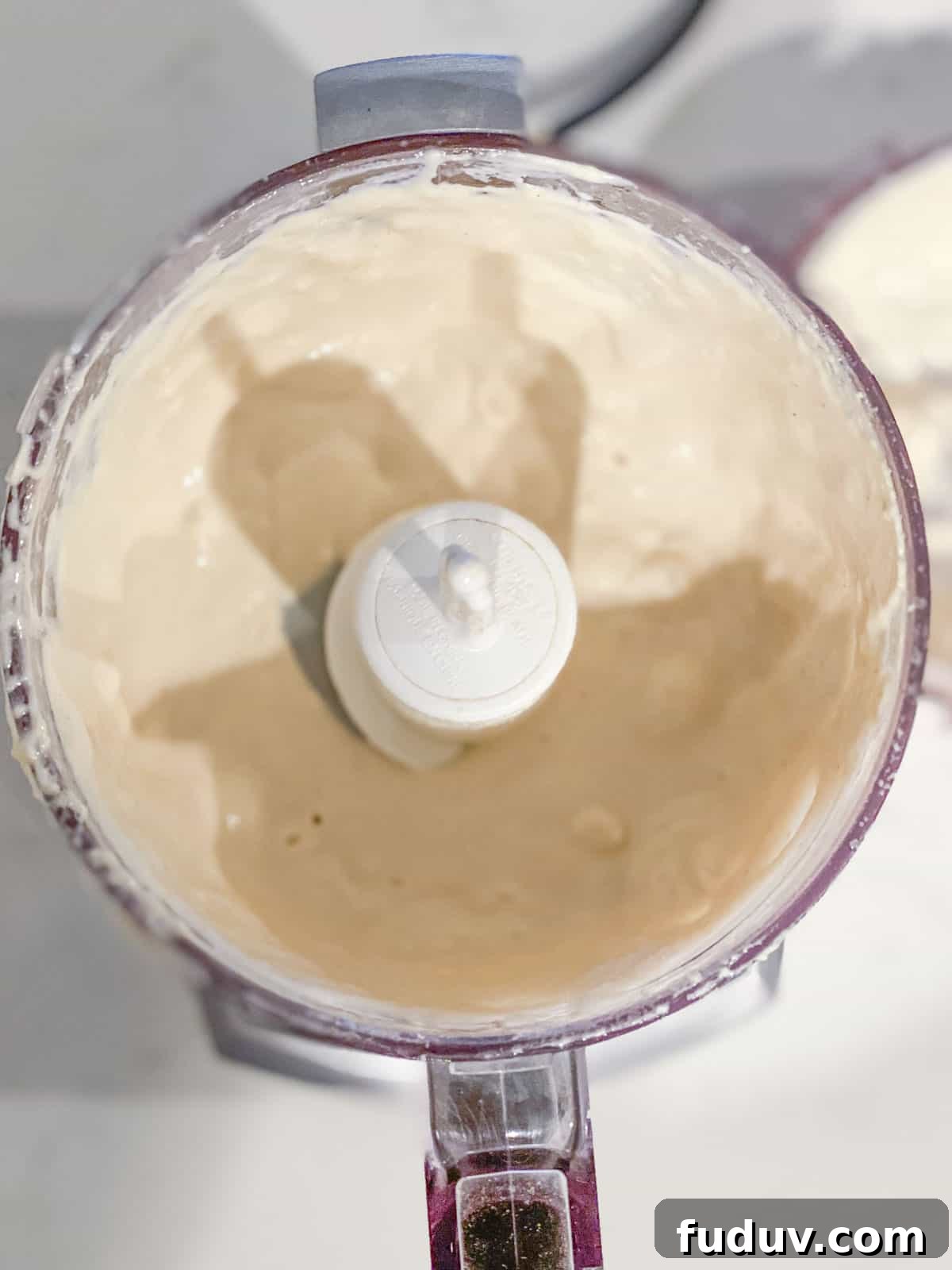 A small food processor with a tahini dressing inside.