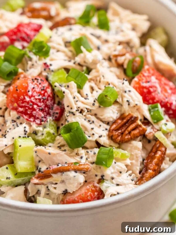 White bowl with strawberry pecan chicken salad topped with green onion and pecans.