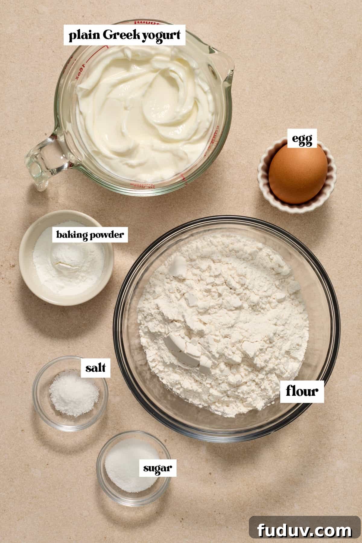 Flour, plain greek yogurt, egg and other ingredients to make recipe on surface.