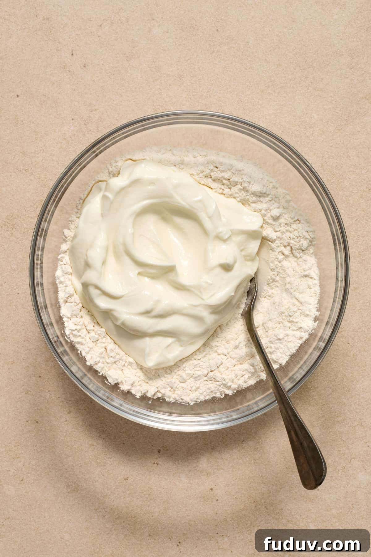 Greek yogurt added to bowl with flour and spoon.