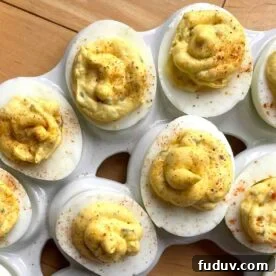 Two rows of cajun deviled eggs on a white platter.