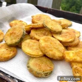 Fried squash slices draining on a paper towel.