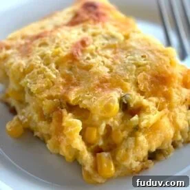 A slice of corn pudding with cheese and jalapeños on a white plate.