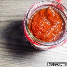 A jar of barbecue sauce with a ribbon around the top on a gray wooden background.