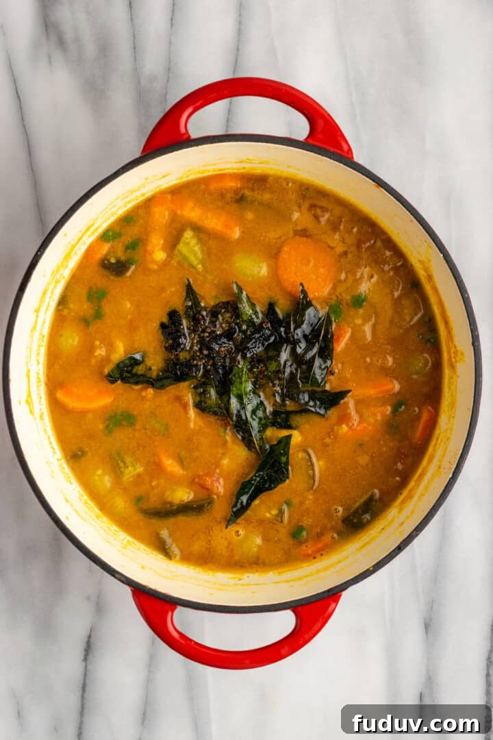 Overhead view of tempering added to pot of sambar