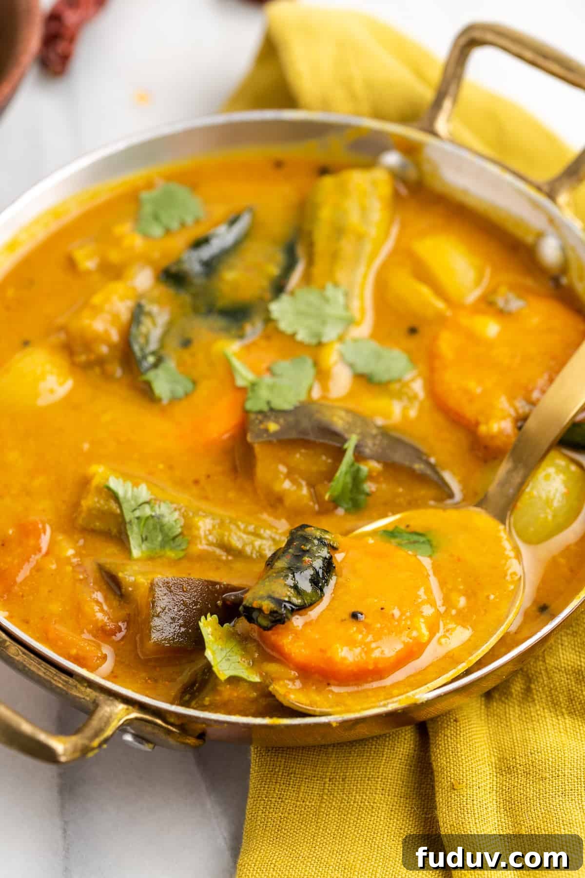 Spoonful of vegan sambar set in serving bowl