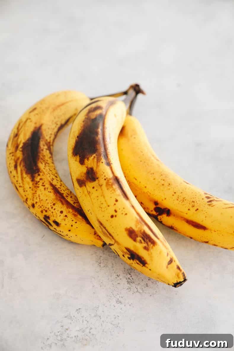 3 ripe bananas with brown spots on a white table