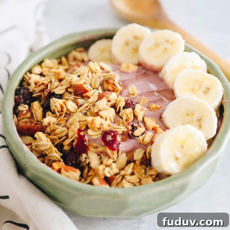 pink smoothie bowl with bananas, granola and honey.