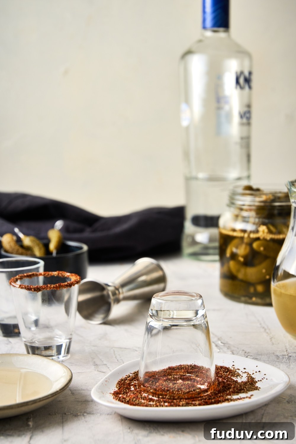 A plate with tajin seasoning and the shot glass being rimmed with it.
